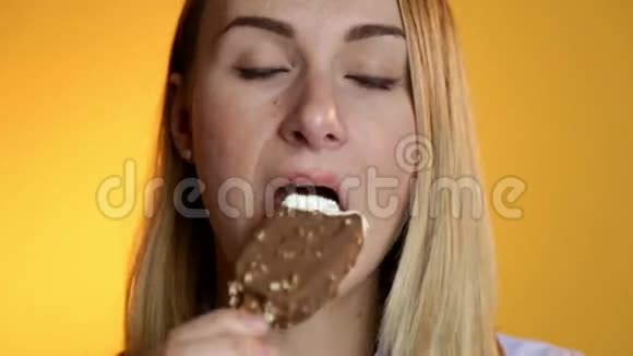 在黄色背景下吃冰淇淋的年轻女人视频的预览图