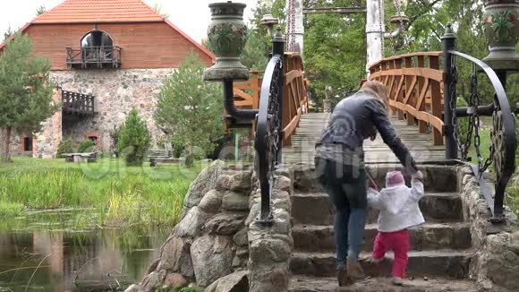 母亲和女婴在公园的石阶桥上散步4K视频的预览图