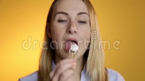 在黄色背景下吃冰淇淋的年轻女人视频的预览图