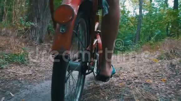 骑着自行车在森林里的小径上骑马的人的腿慢动作视频的预览图