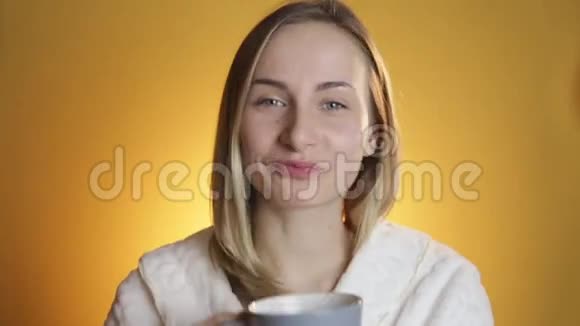 女人在黄色背景的杯子里喝茶视频的预览图