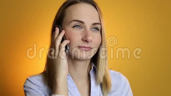 美丽的年轻女子在黄色背景上的手机上交谈视频的预览图