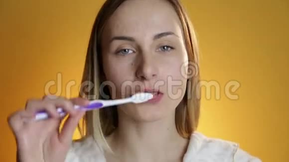 女人刷牙在黄色背景下微笑视频的预览图