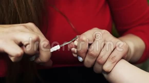 母亲穿着红色衬衫脚上剪着女婴的指甲儿科做母亲儿童视频的预览图
