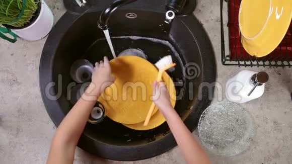 幼儿双手洗一个黄色盘子特写俯视图视频的预览图