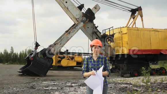 女工人站在一台挖掘机前看着这个计划视频的预览图