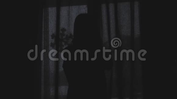 可爱的女孩醒着站在窗前美丽的女人打开窗帘透过窗户看视频的预览图