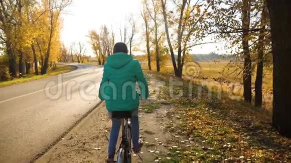 秋天公园黄树背景下的小女孩骑自行车视频的预览图