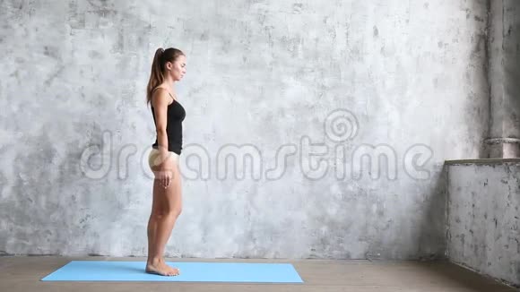 年轻漂亮的女人在蓝色的垫子上在室内练习瑜伽视频的预览图