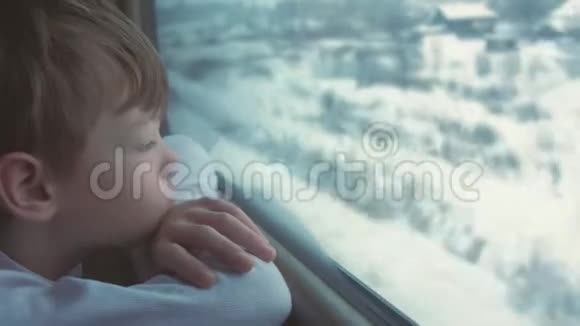 男孩正在窗户里寻找冬天的风景视频的预览图