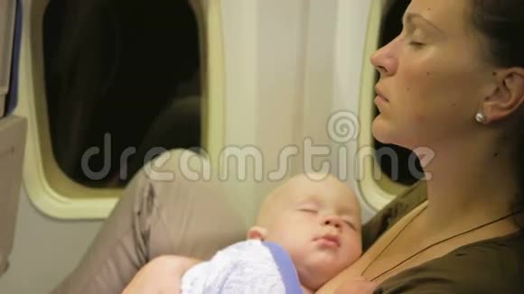 妈妈和宝宝在飞机上休息夜间飞越海洋孩子的眼睛闭着视频的预览图