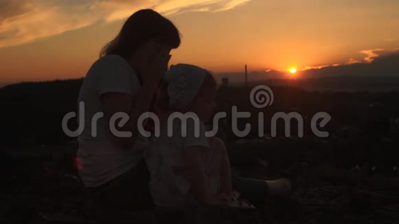 傍晚时分妈妈和女儿正坐在山上视频的预览图