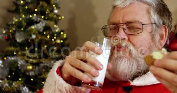 圣诞老人在椅子上放松吃甜食和喝牛奶视频的预览图