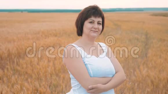 一个胖女人微笑的肖像加上大小时尚模特在慢动作视频白色连衣裙在田间小麦脂肪视频的预览图