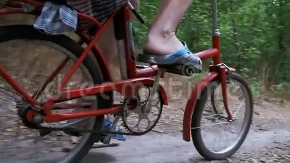 骑着自行车在森林里的小径上骑马的人的腿慢动作视频的预览图