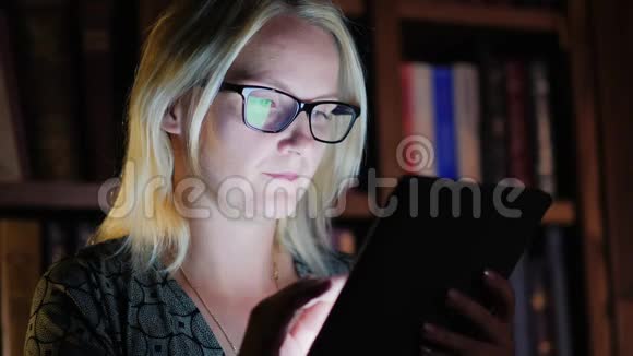 一个女人深夜在图书馆里用平板电脑工作工作到很晚视频的预览图