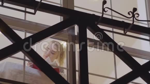 漂亮的金发女郎在窗户上看书视频的预览图