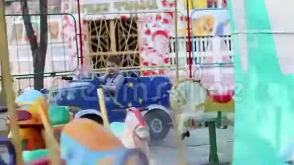 快乐的小可爱的男孩乘着汽车乘旋转木马视频的预览图