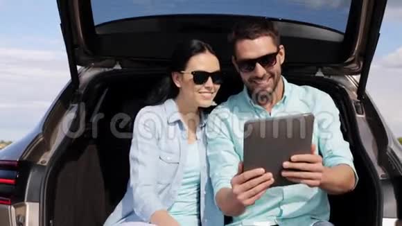 Happy夫妇带平板电脑在掀背车后备箱6视频的预览图