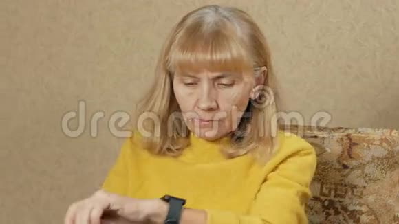 女人的年龄是在家里沙发上的智能手表上留言她仔细阅读了重要的信息视频的预览图