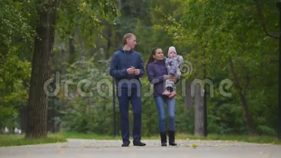 幸福的家庭爸爸妈妈和小女孩在秋天公园散步视频的预览图