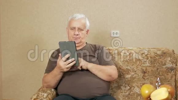 平板电脑时代的男人在家里的沙发上看新闻他翻过手指不感兴趣视频的预览图