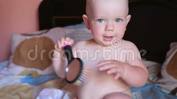 漂亮的宝宝在床上玩梳子微笑并试图梳理自己孩子一年梳子上有一面镜子视频的预览图