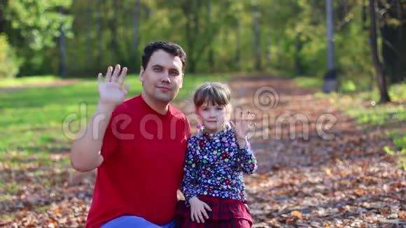 小女孩和她的父亲挥手在阳光明媚的秋天公园玩耍视频的预览图