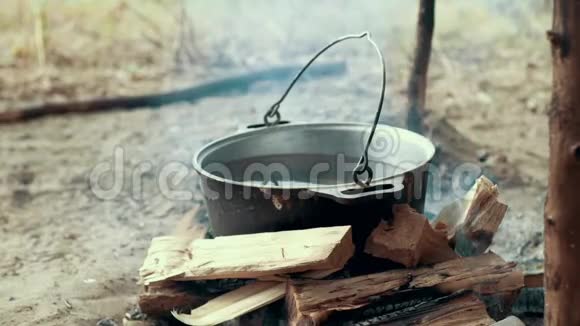 在篝火旁用旅游锅煮远足食品准备野营食品视频的预览图