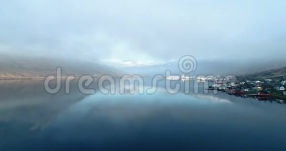 在清晨的阳光下在峡湾和斯堪的纳维亚建筑上空低飞冰岛视频的预览图