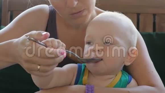 妈妈在咖啡馆里给婴儿喂漂亮的汤孩子舔勺子还想吃穿绿色T恤的金发男孩视频的预览图