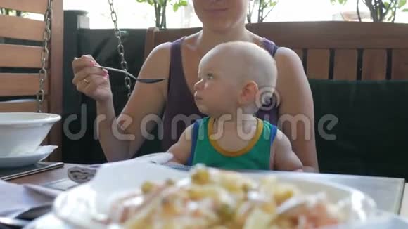 在意大利年轻的母亲正在用她的大腿意大利面喂养婴儿孩子1年了穿着绿色T恤视频的预览图