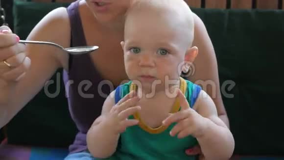 妈妈在咖啡馆里给婴儿喂漂亮的汤孩子舔勺子还想吃穿绿色T恤的金发男孩视频的预览图
