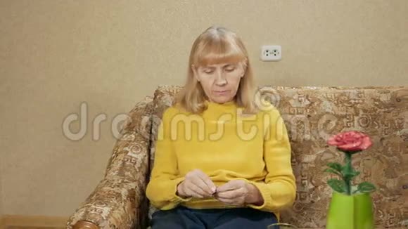 生病的老年妇女在家里的沙发上吃药在玻璃杯里喝水她制造了几种光滑的液体这就是视频的预览图