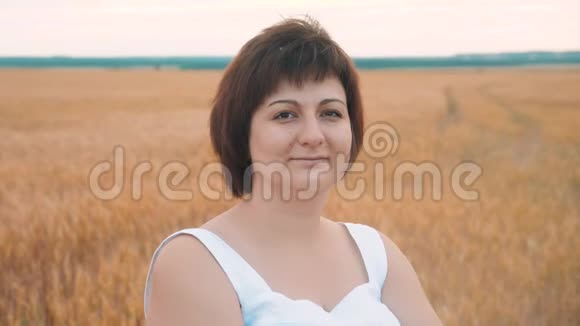 一个胖女人微笑的肖像加上大小时尚模特在慢动作视频白色连衣裙在田间小麦脂肪视频的预览图