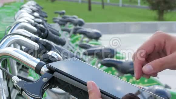 一个男人在自行车停车场检查平板电脑上的信息他要租一辆自行车视频的预览图