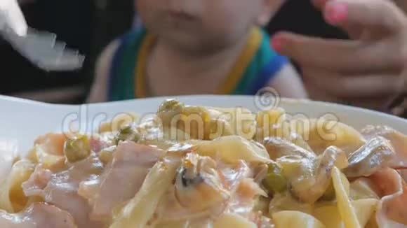 在意大利年轻的母亲正在用她的大腿意大利面喂养婴儿孩子1年了穿着绿色T恤视频的预览图