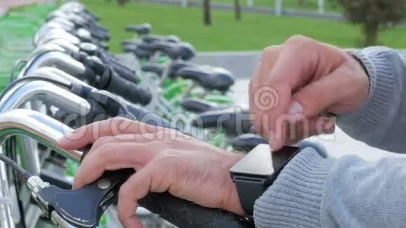 一个男人在自行车停车场检查智能手表上的信息他要租一辆自行车视频的预览图