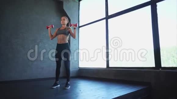 做健身运动的漂亮女人她在健身房举起哑铃体育训练视频的预览图