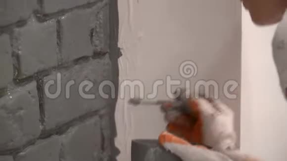 一只戴手套的雌性手用画笔在灰色的砖墙上作画视频的预览图