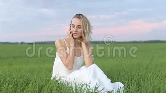 可爱的年轻女人在草地上用手机说话视频的预览图
