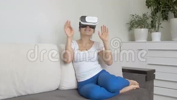 年轻女子戴着虚拟现实耳机坐在沙发上4K拍摄的录像视频的预览图