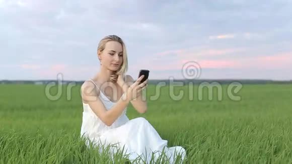 金发女孩在草地上打自助电话视频的预览图