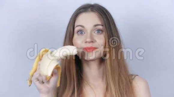 年轻开朗的女人带着红色口红在工作室吃香蕉视频的预览图
