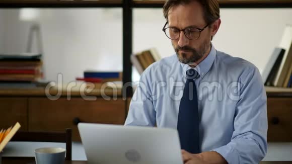 专心致志的商人坐着用他的笔记本电脑视频的预览图