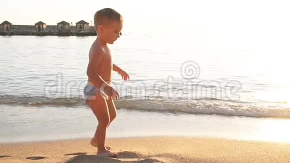 小男孩正在沙滩上散步慢动作视频的预览图