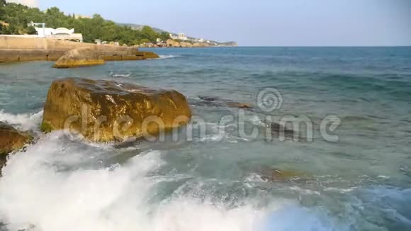缓慢的海浪拍打着蓝天上的岩石视频的预览图