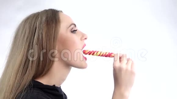 漂亮的女孩舔棒棒糖白色的慢动作视频的预览图