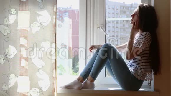 窗台上有智能手机的年轻女子视频的预览图