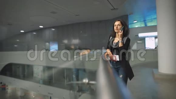 一个年轻快乐的女人在机场边打电话边微笑视频的预览图
